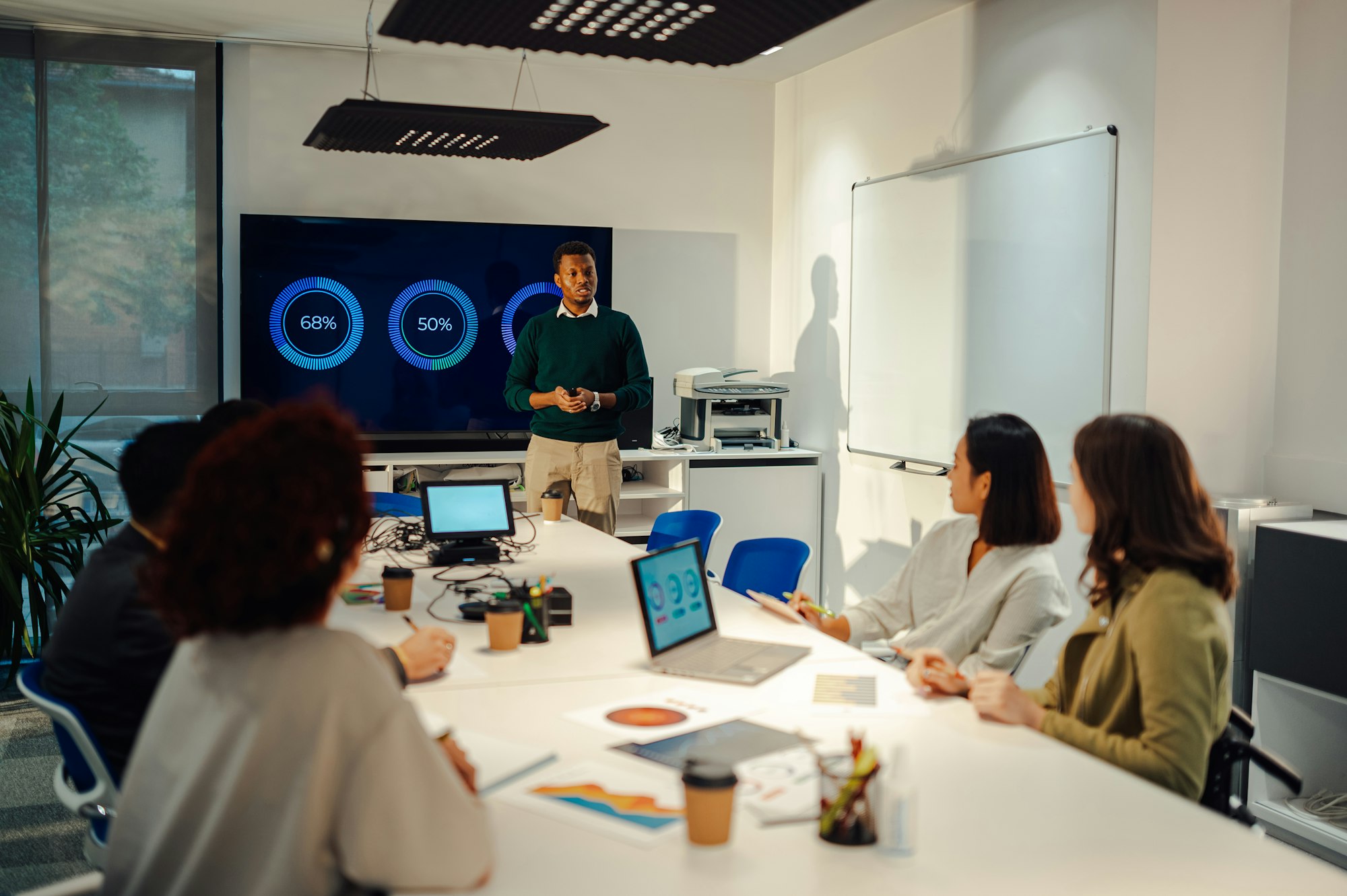 African american male team leader using chart on a digital screen on a meeting